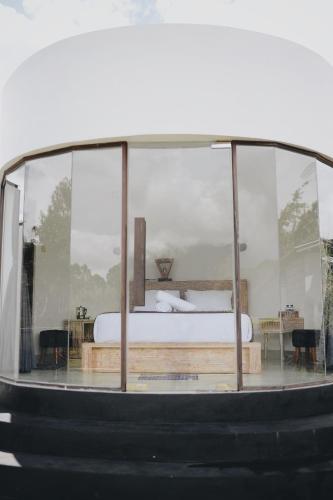 a bedroom with a bed in a glass house at Batur Cozy Bali in Kintamani
