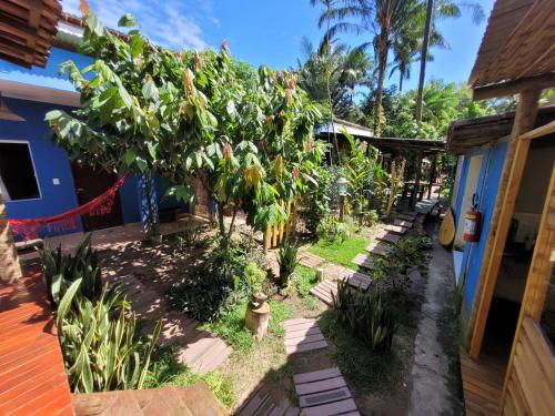 a garden with banana trees and a blue house at Villa Residencial Encantos Da Mata in Itacaré