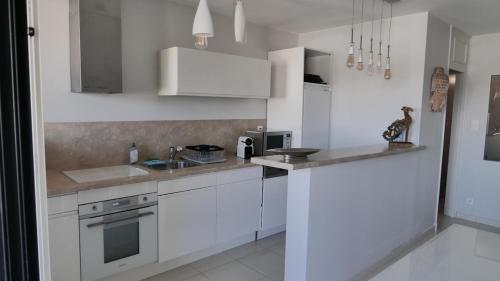 une cuisine blanche avec des armoires blanches et un évier dans l'établissement LA GALIOTTE SUR LE GOLFE DE ST TROPEZ, à Cogolin