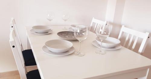 a white table with wine glasses and plates on it at Carachouse-Lido di Camaiore, tra pini marini e mare in Lido di Camaiore