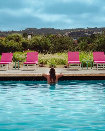 a woman laying in the water in a swimming pool at Flamboyant Boutique B&B in Caldas da Rainha