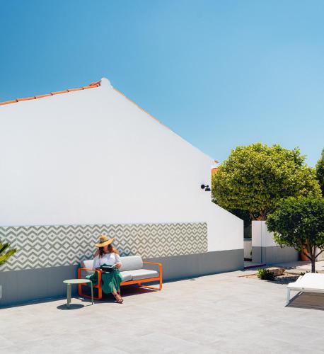 a woman sitting on a bench next to a wall at Flamboyant Boutique B&B in Caldas da Rainha