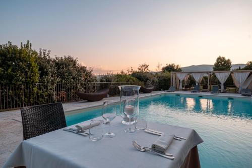 einen Tisch mit Gläsern und Servietten neben einem Pool in der Unterkunft Villa Giorgia Albergo in Collina in Pistoia