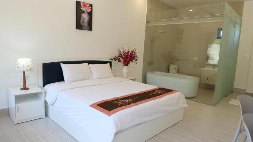 ein Schlafzimmer mit einem großen Bett und einer Badewanne in der Unterkunft Green Star Premium Resort - Mui Ne - Formerly Hung Thinh Resort in Ấp Long Sơn