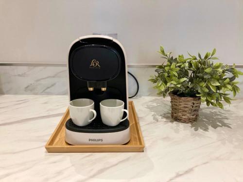 a coffee maker with two cups on a wooden tray at Le Pearl Appartement de charme en bord rivière in Collobrières