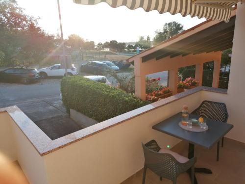 a table and chairs on a balcony with a view of a parking lot at Apartment Mari in Funtana