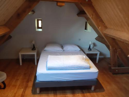 Ce lit se trouve dans une chambre mansardée avec 2 tables. dans l'établissement Gite avec charme entre Collonges la rouge-Turenne, à Ligneyrac
