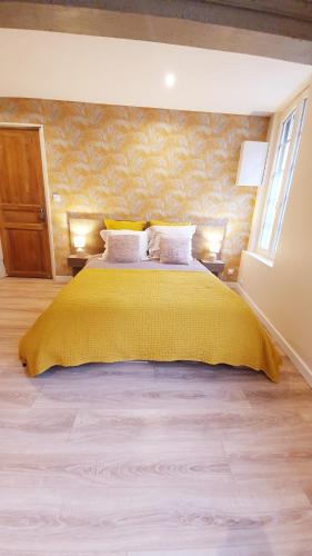 une chambre avec un grand lit avec un couvre-lit jaune dans l'établissement Nid du puits : charmant studio centre Honfleur, à Honfleur