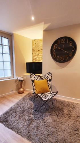 une chaise dans une pièce avec une horloge sur le mur dans l'établissement Nid du puits : charmant studio centre Honfleur, à Honfleur