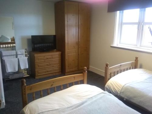 a bedroom with two beds and a tv and a cabinet at White Horse Hotel in Strichen