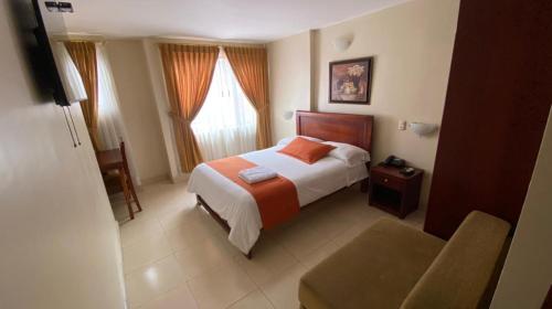 a hotel room with a bed and a chair at Hotel Caluva in Loja