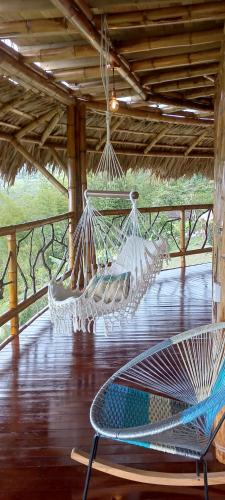 a porch with a hammock and a chair on a deck at Ecohotel Soplo del Tambo in Cocorná