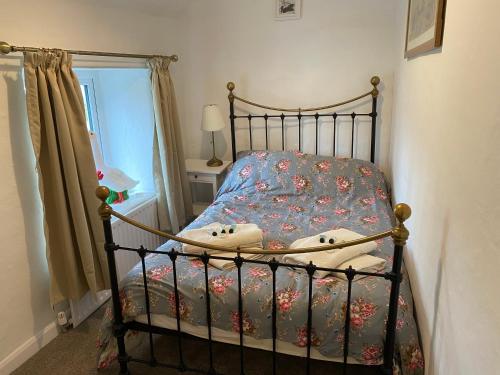 a small bedroom with a bed with a bedspread with flowers at Primrose cottage in Tideswell