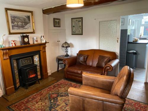 a living room with a couch and a chair and a fireplace at Primrose cottage in Tideswell