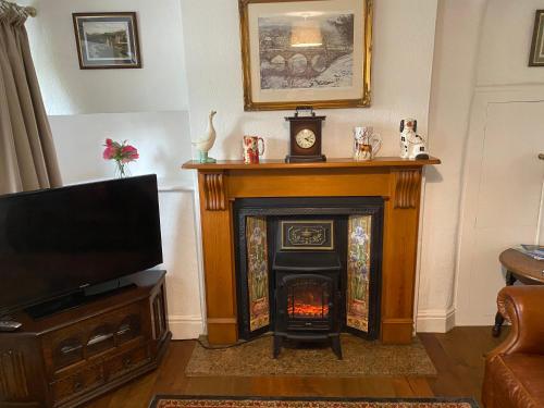 a living room with a fireplace and a television at Primrose cottage in Tideswell
