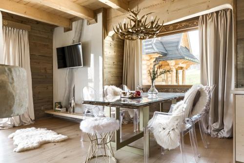 a dining room with a table and white chairs at NA SKRAJU LASU domki z balią, jacuzzi in Biały Dunajec