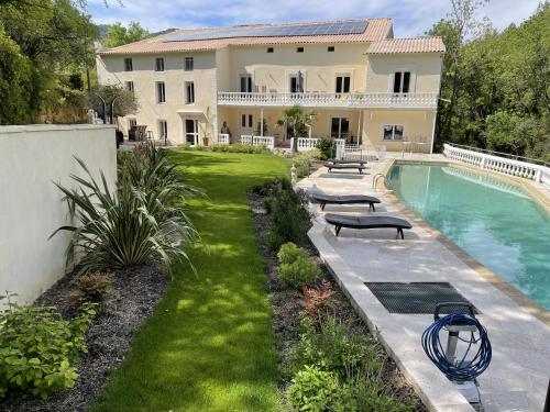 a house with a swimming pool in front of a yard at MOULIN DE L'OULETTE in Soubès