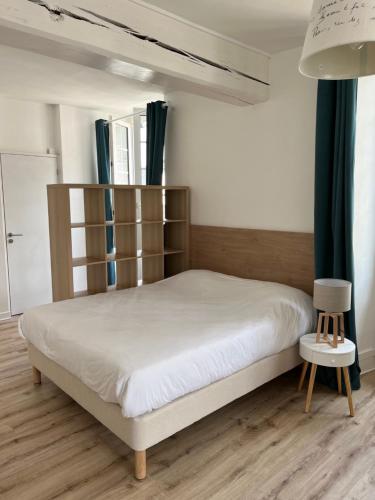 1 dormitorio con 1 cama con cabecero de madera en Appart'hôtel La Suze sur Sarthe, en La Suze-sur-Sarthe