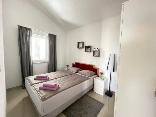 ein Schlafzimmer mit einem Bett mit rosa Kissen darauf in der Unterkunft Apartment Larus in Vir