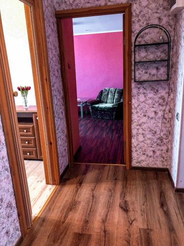 a door leading to a living room with pink walls at Dzelmes in Kolka