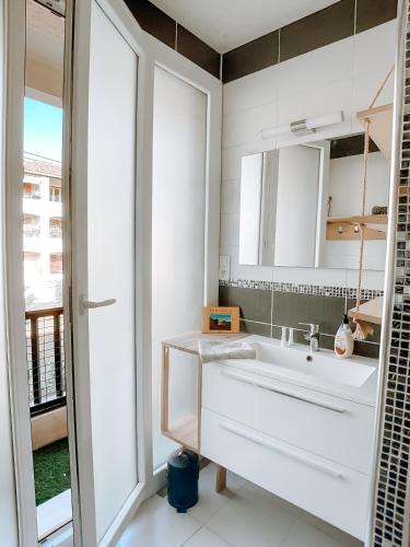 une salle de bain blanche avec un lavabo et une fenêtre dans l'établissement Appartement T3 tout confort à 500m de la mer, à Saint-Cyr-sur-Mer