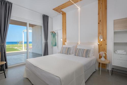 Schlafzimmer mit einem weißen Bett und Meerblick in der Unterkunft Niva Kamiros Apartments in Kamiros