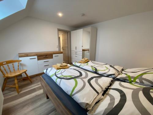 a bedroom with a large bed and a chair at Pension Pradler Wohnung Obergeschoß in Carolinensiel