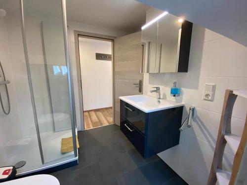 ein Bad mit einem Waschbecken und einer Dusche in der Unterkunft Pension Pradler Wohnung Obergeschoß in Carolinensiel