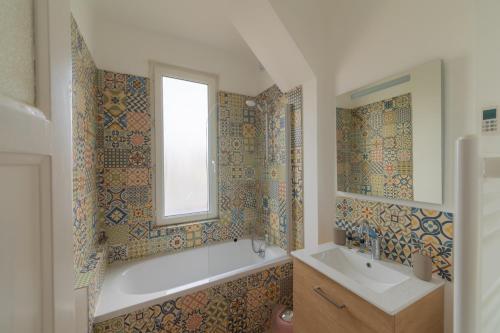 La salle de bains est pourvue d'une baignoire, d'un lavabo et d'une fenêtre. dans l'établissement Appartement Cosy avec garage privé, au Mans
