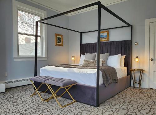 a bedroom with a black canopy bed with a stool at Little Fig Hotel in Bar Harbor