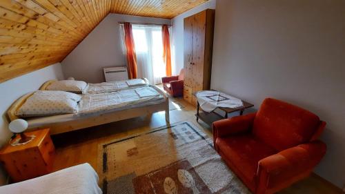 a bedroom with a bed and a chair and a window at Magdaléna Ház in Balatonlelle