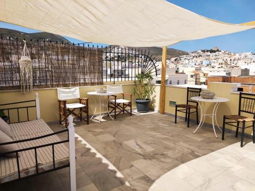 a patio with tables and chairs and a view of a city at Fiera Guesthouse in Ermoupoli