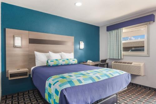 a hotel room with a bed and a blue wall at Knights Inn and Suites Salem in Salem