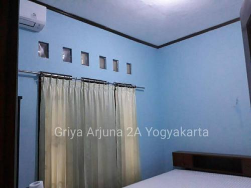a bedroom with blue walls and a curtain at Griya Arjuna 2A in Yogyakarta