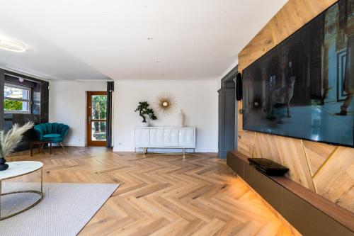 a living room with wooden flooring and a large flat screen tv at Serenity Prague Villa with garden jacuzzi in Prague