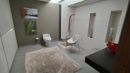 a bathroom with a toilet and a table and a chair at Amonita casa Campestre, vía Tunja Paipa in Tunja