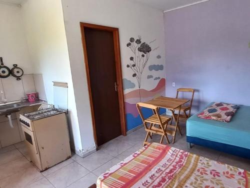 イビコアラにあるPousada Serra Aquarela - Mini casasのキッチン、テーブル、ベッドが備わる客室です。