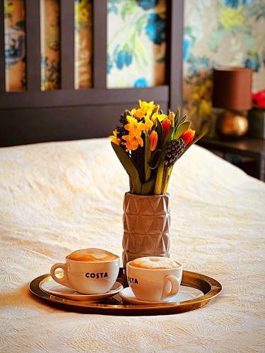 two cups of coffee and a vase with flowers on a table at Latitude Chinatown Central Apartment in Birmingham