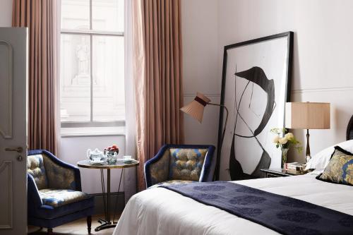 a hotel room with a bed, desk, mirror and window at NoMad London in London