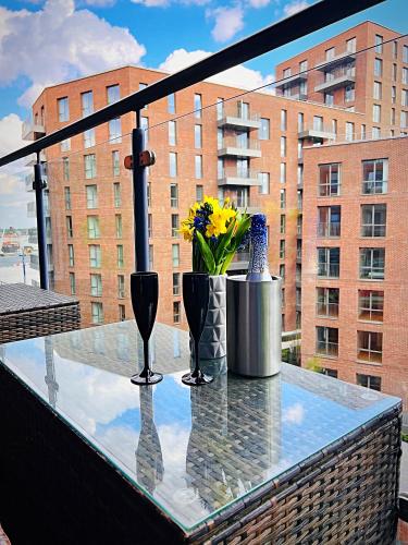 a glass table with vases and flowers on a balcony at Latitude Chinatown Central Apartment in Birmingham