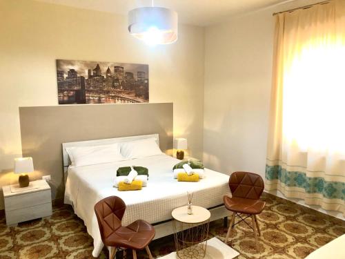 una camera con un letto bianco e due sedie di City B&B a Castelsardo