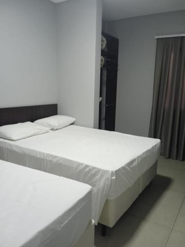 two beds in a room with white walls at Vila Dumont no Centro de Foz in Foz do Iguaçu