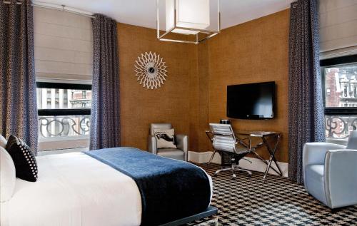 a hotel room with a bed and a desk and a tv at Ameritania at Times Square in New York