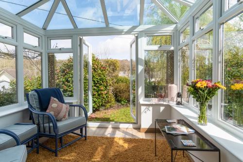 a conservatory with a chair and a table and windows at Finest Retreats - Tinners Rest in St Austell