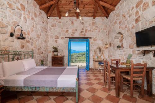 a bedroom with a bed and a table and a television at Strofilia Stone Residences in Volímai