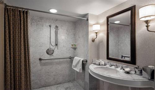 a bathroom with a sink and a mirror and a shower at Washington Duke Inn & Golf Club in Durham