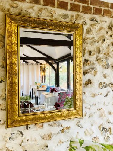 a gold mirror hanging on a stone wall at Château Corneille in Vieux-Villez