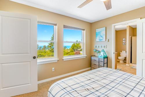 a bedroom with a bed and two windows at Wind 'N Sails in Pacific City