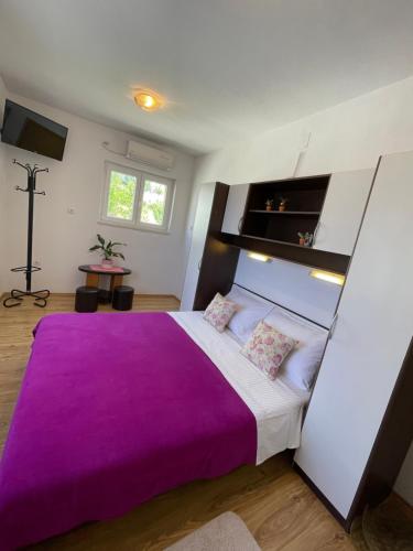 a bedroom with a large bed with a purple blanket at Guesthouse MM in Dubrovnik