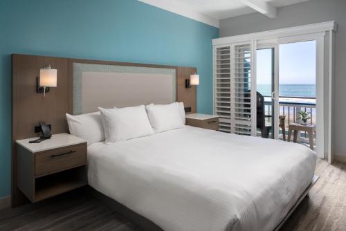 a bedroom with a large white bed and a balcony at Shoreline Inn...on the beach in Cayucos